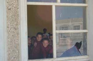Afghan school children look through a broken classroom window